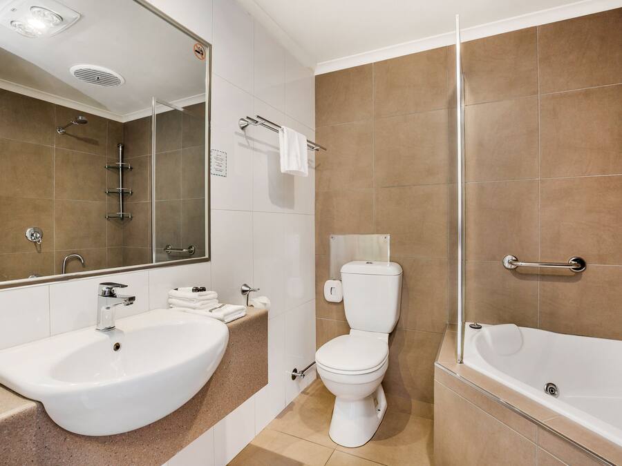 A modern bathroom with a sink, toilet, and bathtub.
