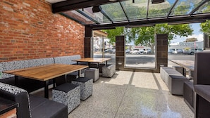 An outdoor seating area with brick walls, a glass enclosure, and a view of the street. - National Hotel Complex and Bendigo Central Apartments (Bendigo)