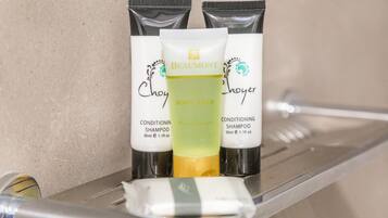 A bathroom shelf with three bottles of Beaumont body wash and two bottles of conditioning shampoo.