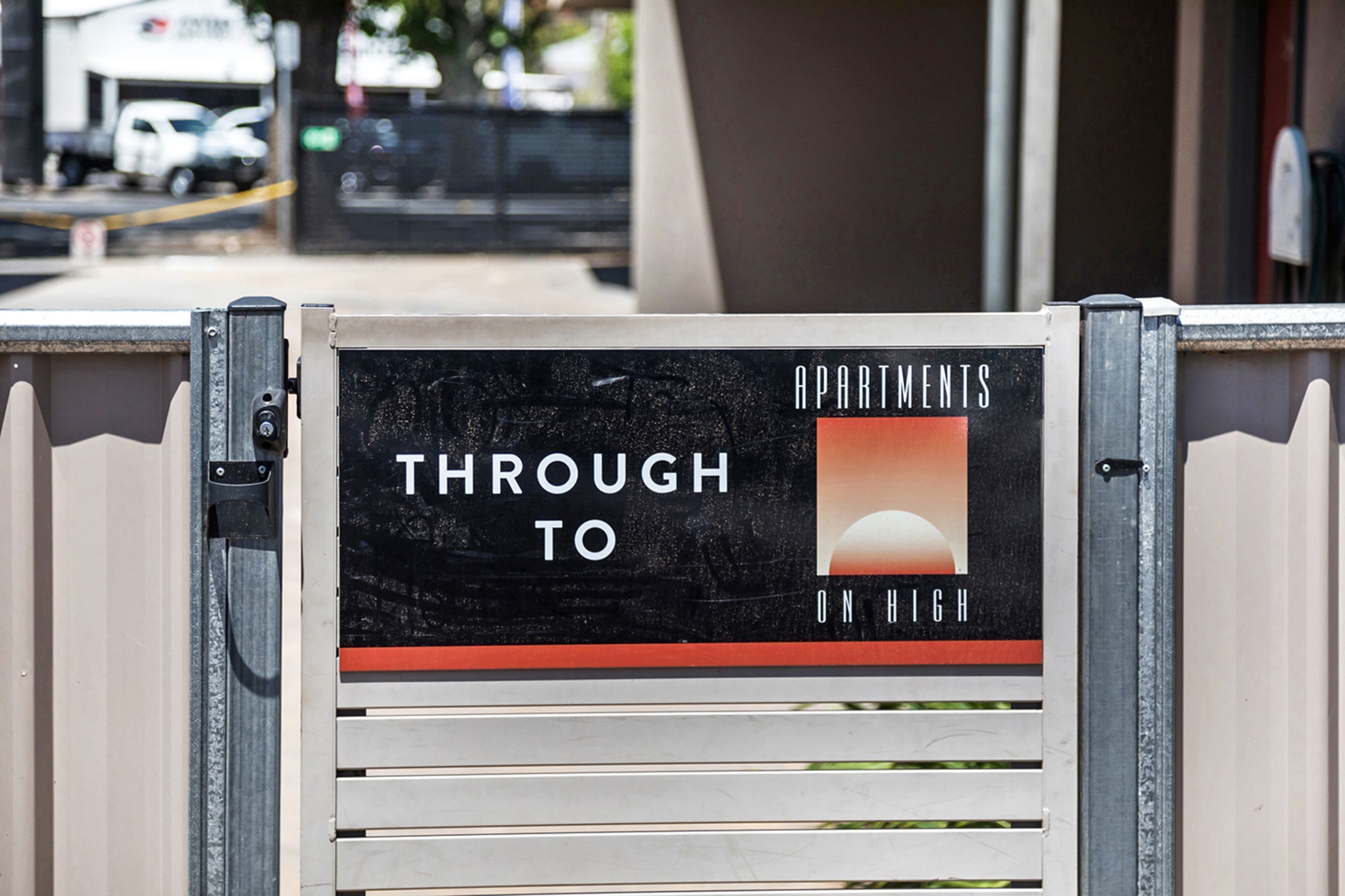 A sign on a gate indicating 'Apartments Through to On High'.