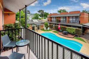 Un balcón con piscina, mobiliario exterior y vistas a edificios cercanos.