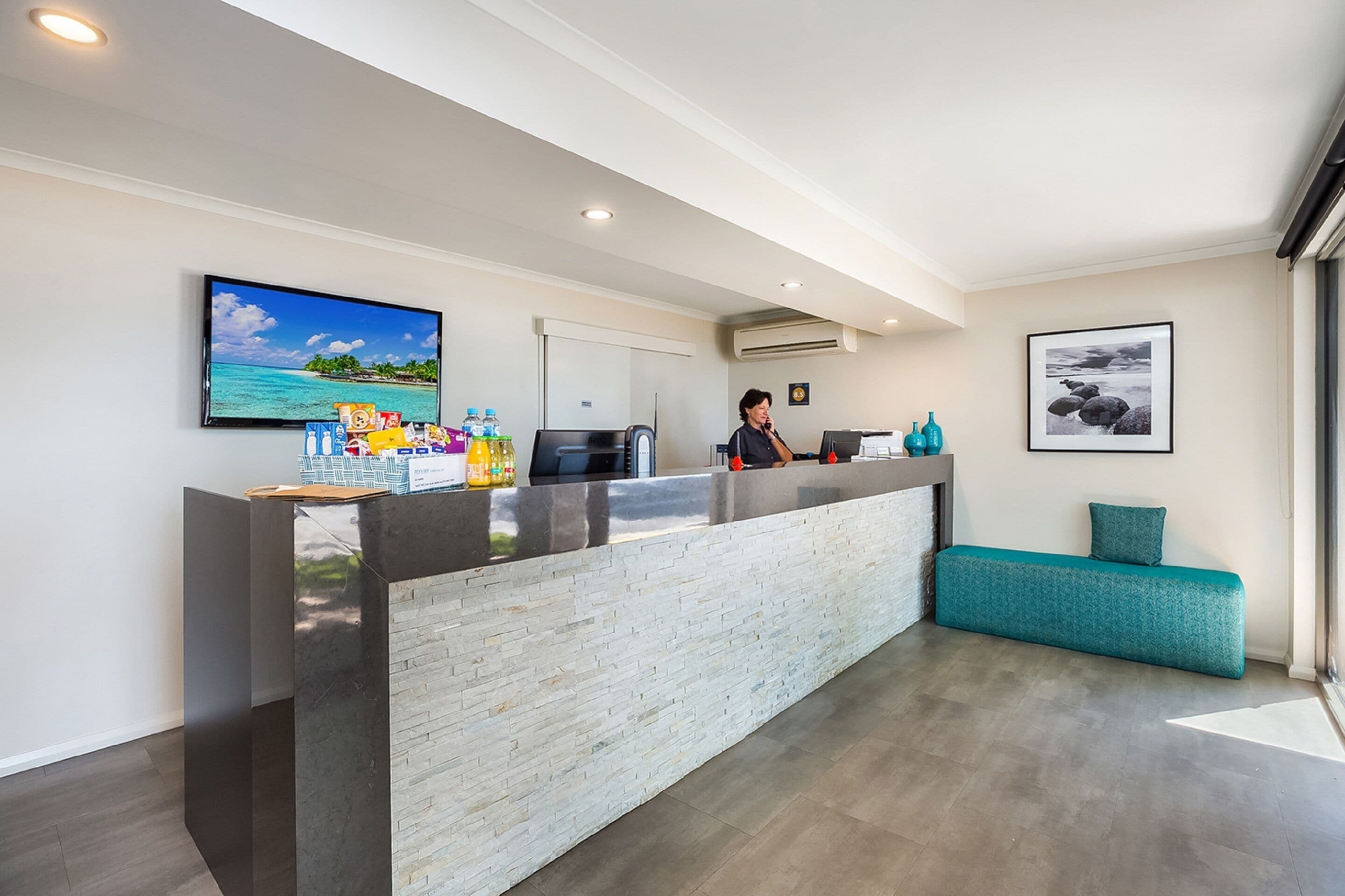 Un área de recepción con mostrador, televisor y sofá.