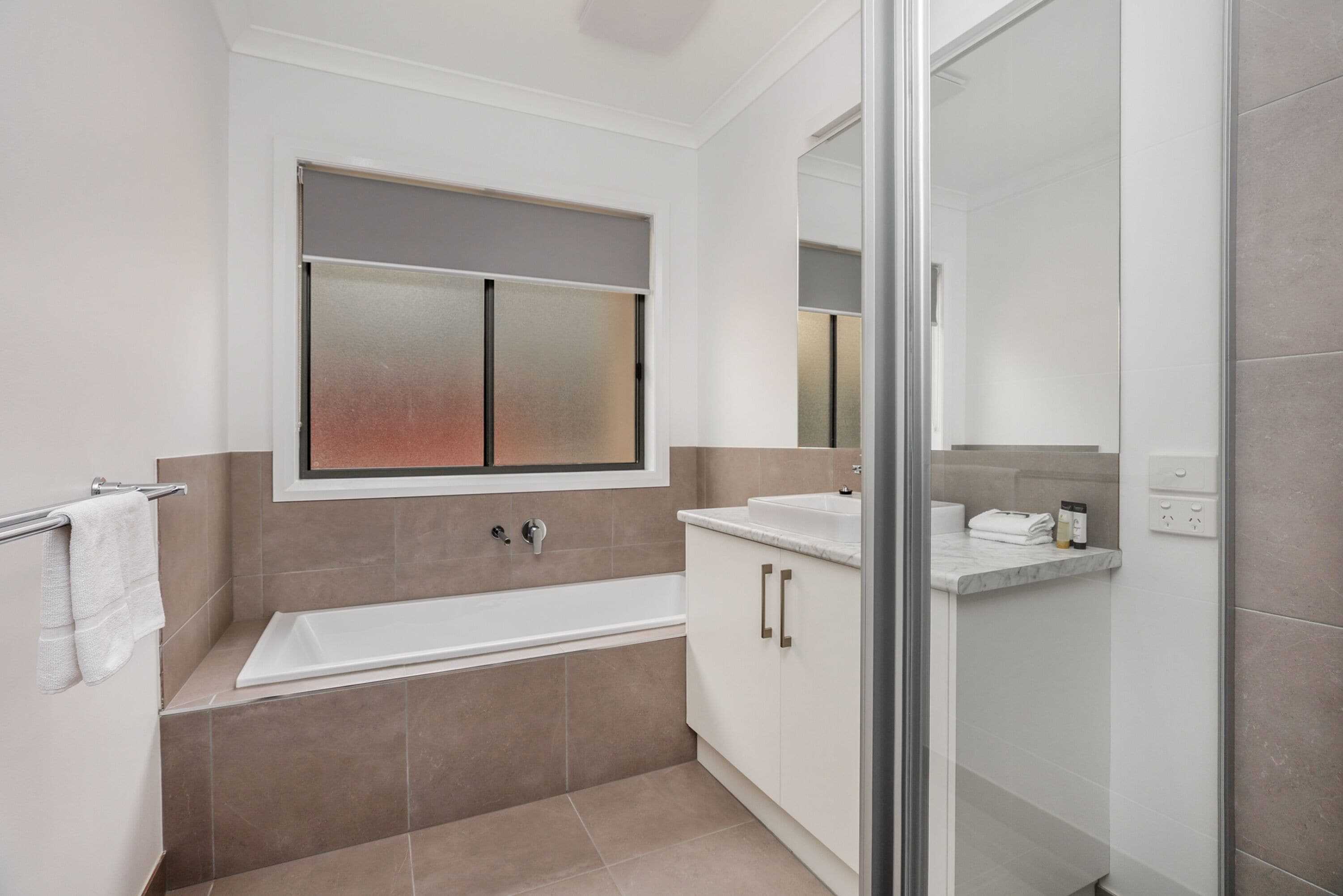A modern bathroom with a bathtub, a glass shower enclosure, and a vanity with a sink.