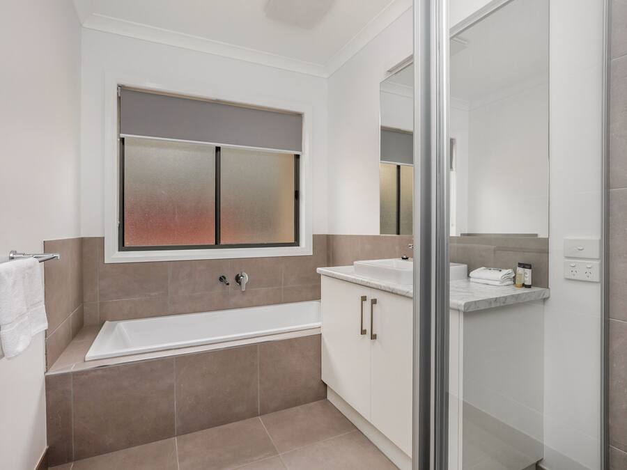 Une salle de bain moderne avec une baignoire, une douche à l’italienne et un meuble-lavabo.