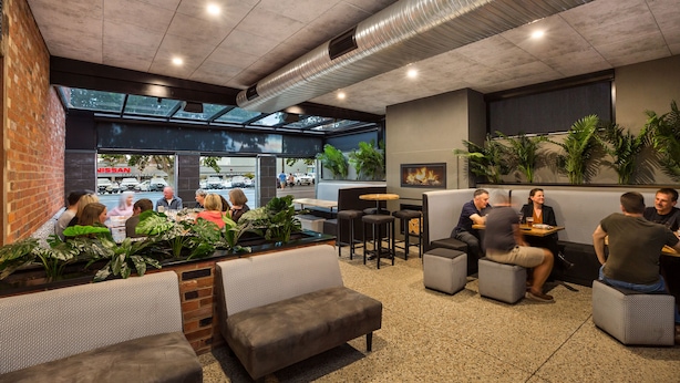 A modern indoor seating area with brick walls, large windows, and potted plants. - National Hotel Complex and Bendigo Central Apartments (Bendigo)