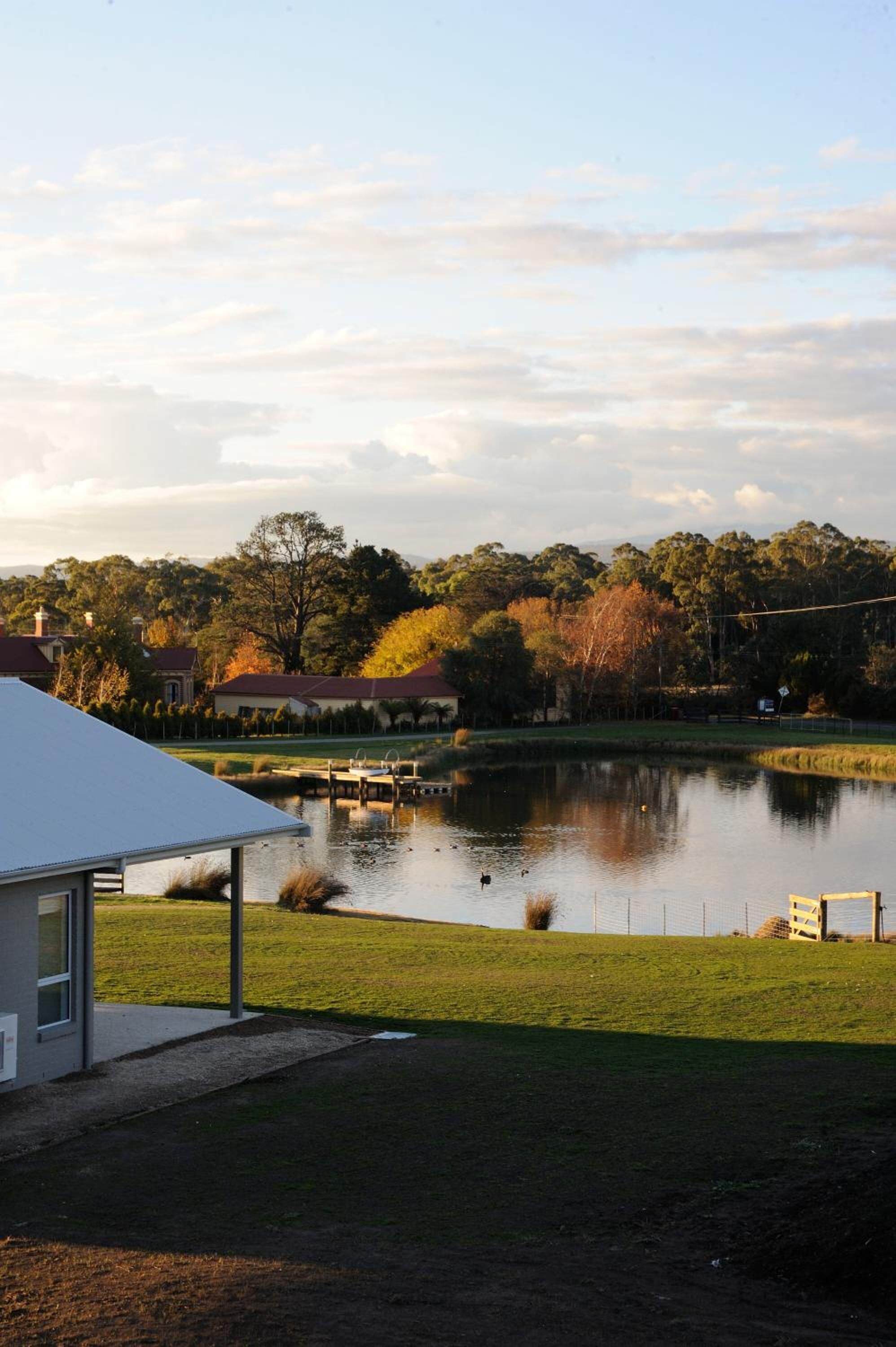 A lakeside view with a building, a dock, and a fence.