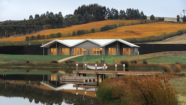 A modern house with a large deck and a boat dock, surrounded by a lake and autumn foliage. - Relbia Lodge (Relbia)