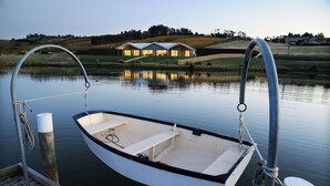 A small boat docked at a wooden pier with a house in the background. - Relbia Lodge (Relbia)