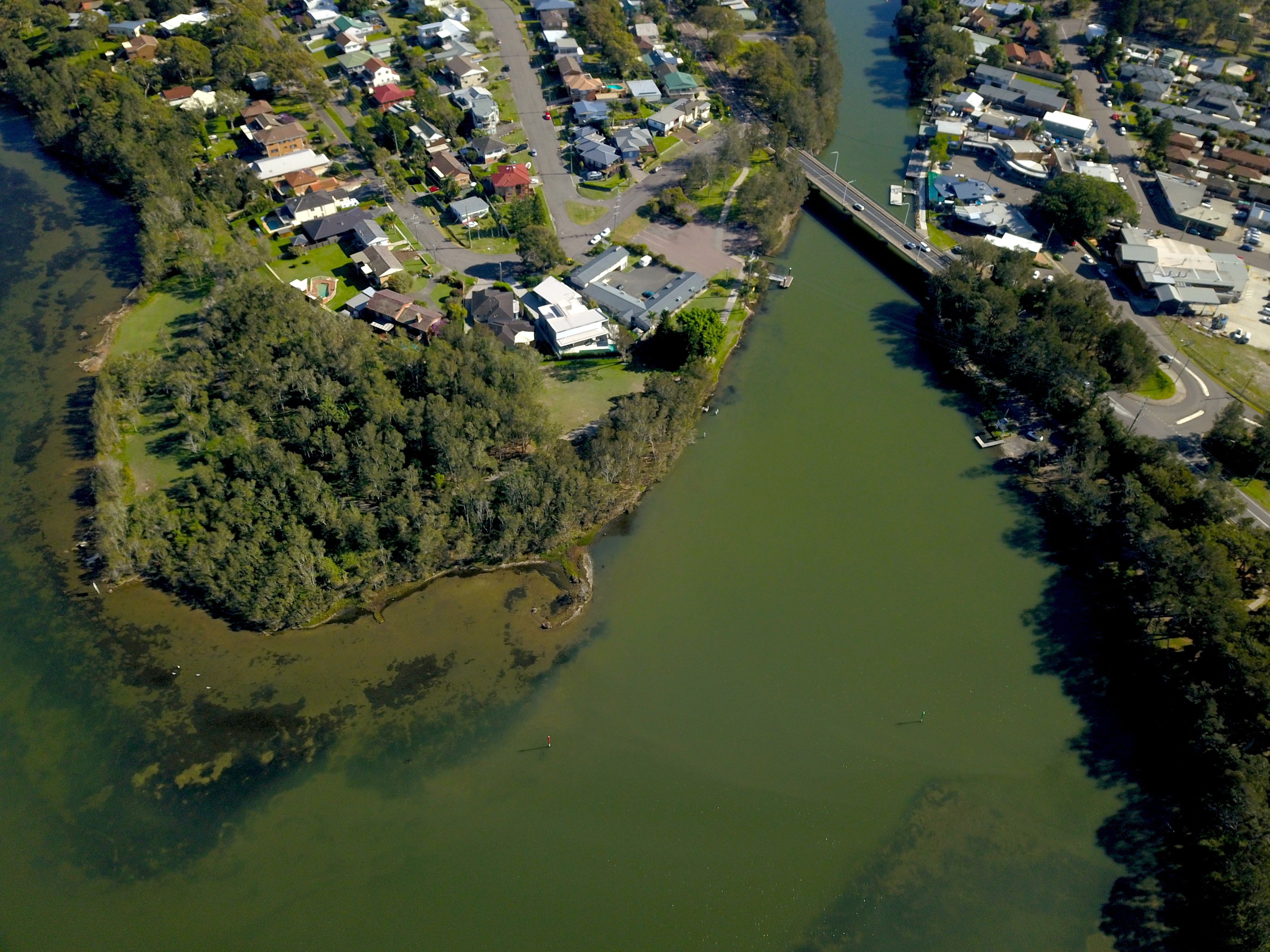 Vue aérienne d’un quartier résidentiel avec des maisons, un pont et une rivière.
