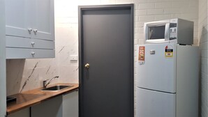 A compact kitchen with a dark door, a microwave, and a sink. - Hibiscus Lakeside Motel (Budgewoi)