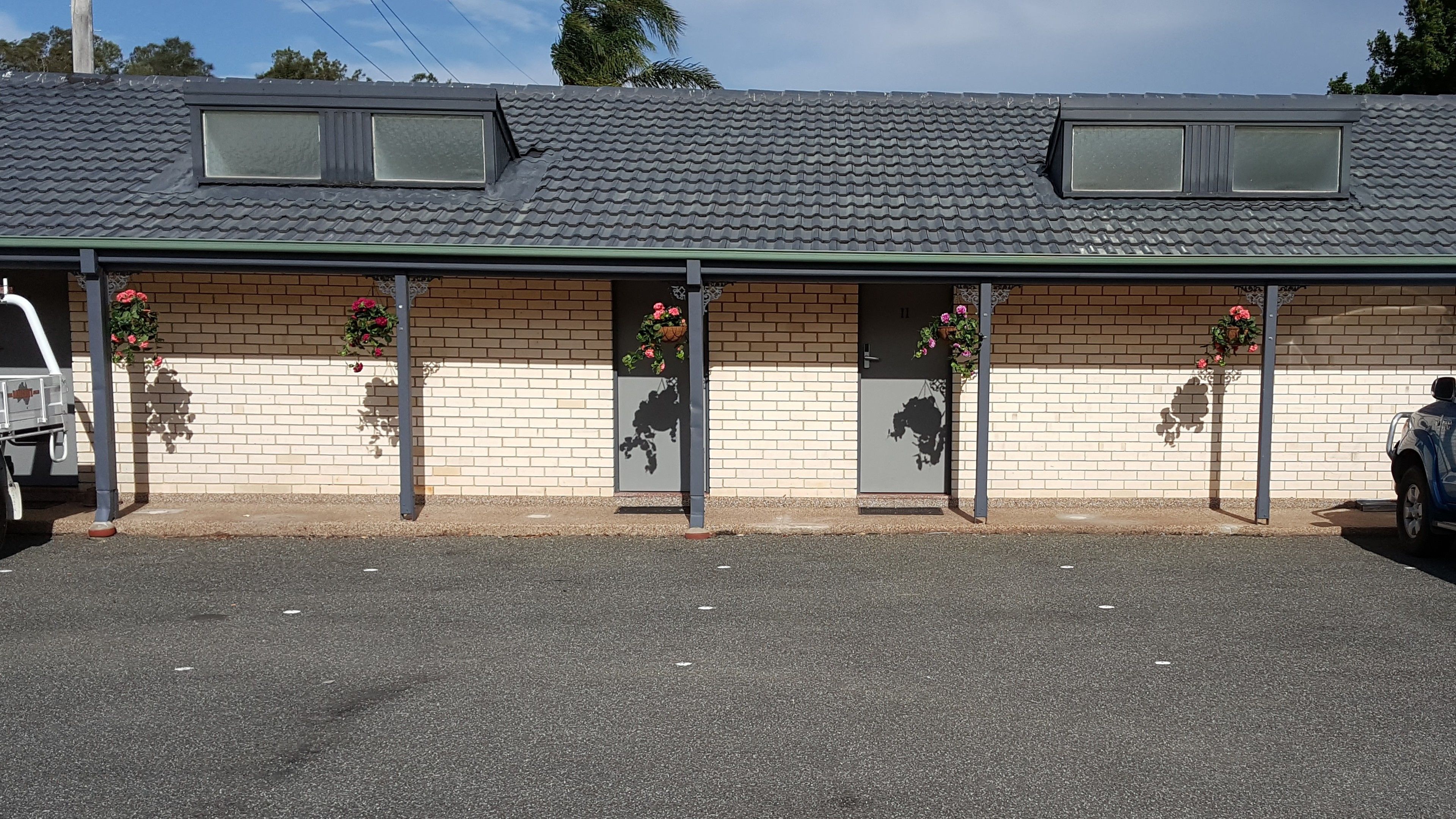 A building with a tiled roof, brick walls, and multiple windows. There are flower baskets on the exterior walls.