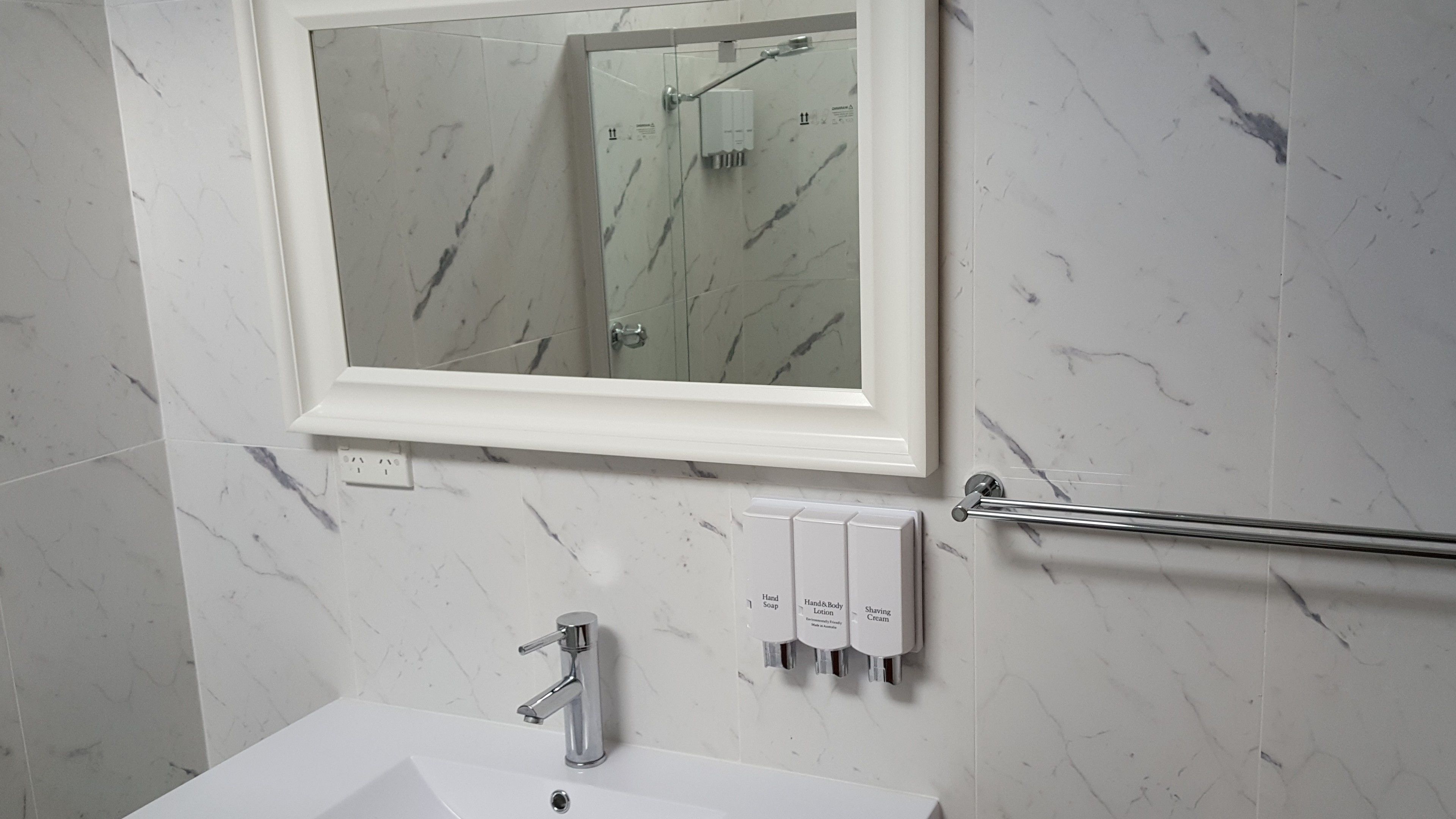 A bathroom with a white sink, a mirror, and a hand soap dispenser.