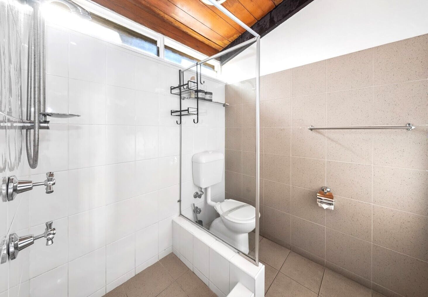 A modern bathroom with a glass shower enclosure, a toilet, and a bathtub.