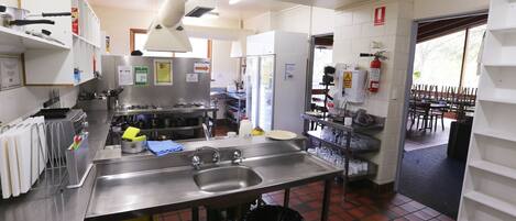 A commercial kitchen with stainless steel appliances, a large sink, and a trash bin.
