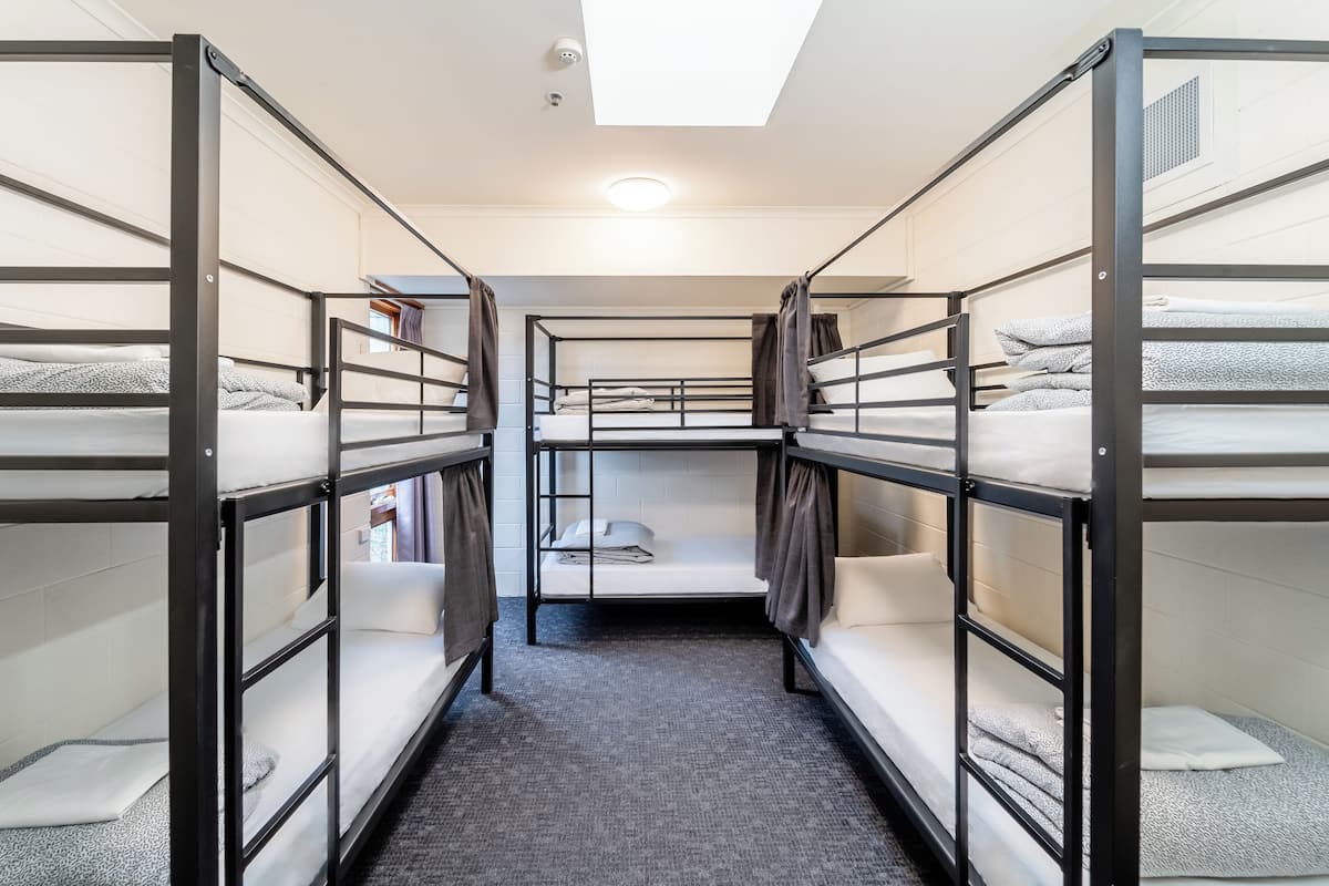A narrow corridor with bunk beds on either side, a skylight above, and a carpeted floor.