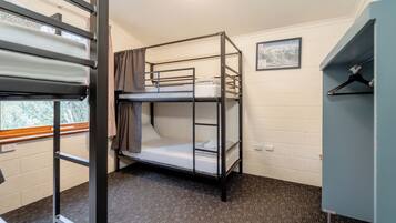 A bunk bed room with a window, a picture on the wall, and a wardrobe.