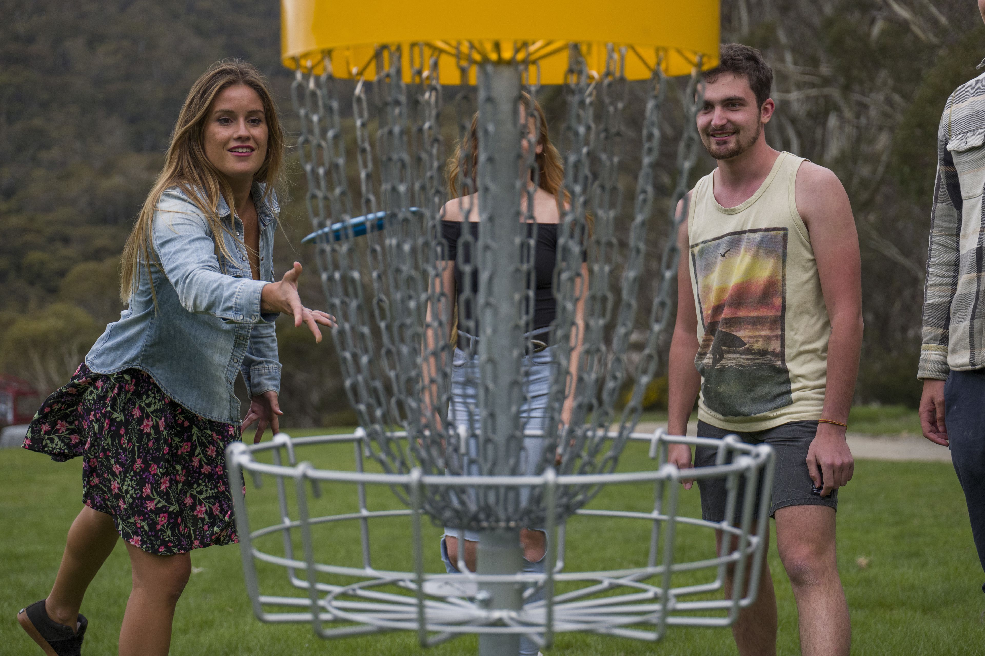A disc golf basket with a chain-link fence.