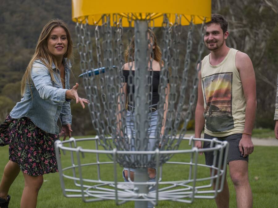 A disc golf basket with a chain-link fence.