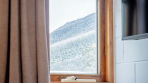 A bedroom with a window overlooking a snowy mountain. - YHA Thredbo (Thredbo)