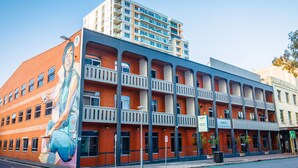 Un hotel de varios pisos con un mural en la fachada, balcones y un letrero que dice 'Ayo'.