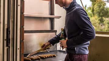 A person grilling sausages on an outdoor grill.