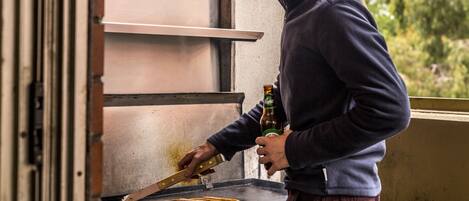 A person grilling sausages on an outdoor grill.