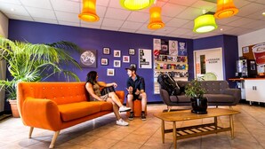Un vestíbulo con pared morada, sofá naranja y un letrero que indica la sala de equipaje.