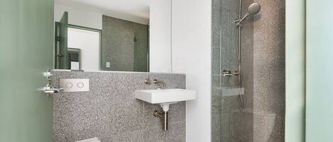 A modern bathroom with a glass-enclosed shower, a white sink, and a toilet.