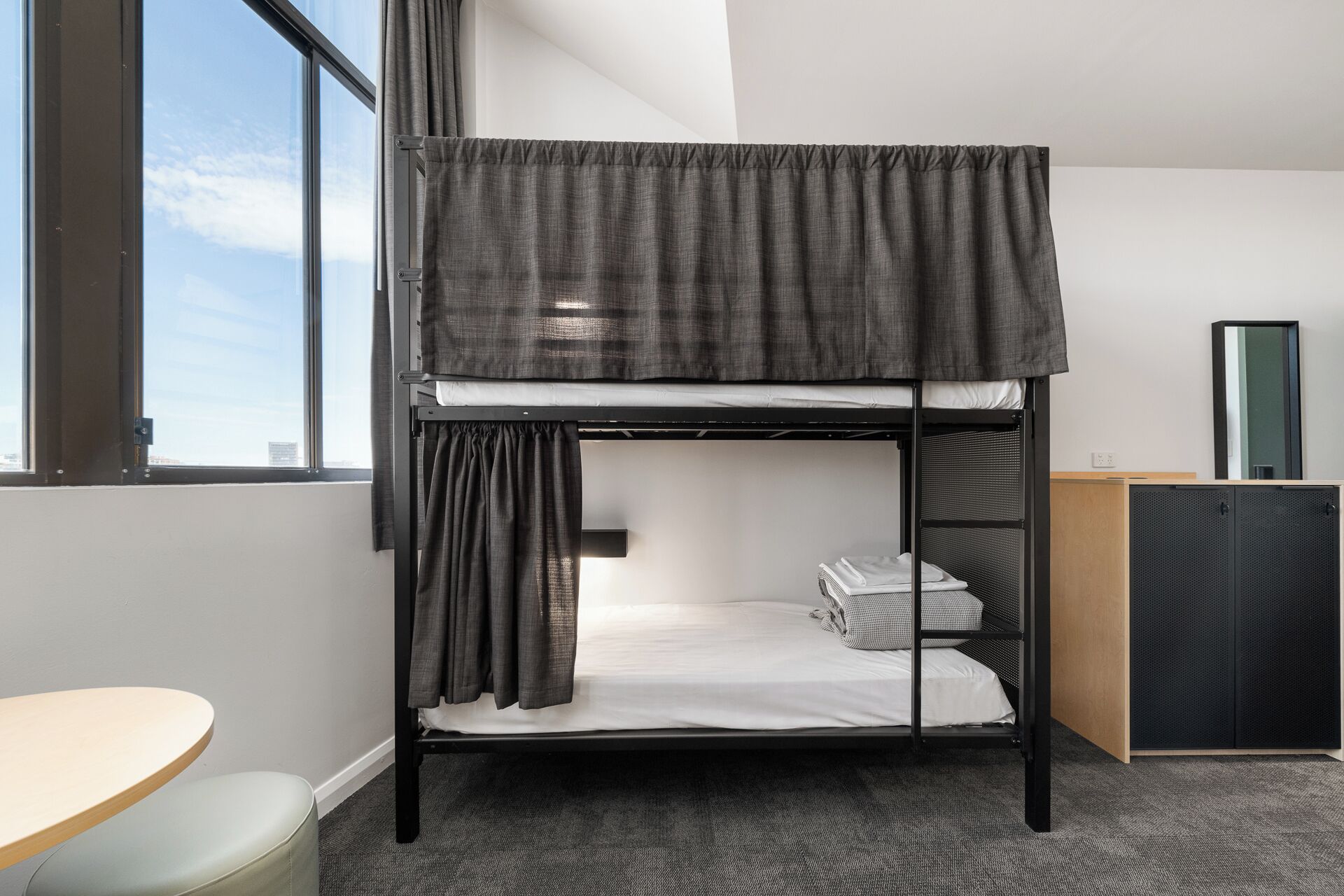 Un lit superposé avec un bureau et un placard dans une pièce dotée d’une fenêtre.