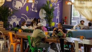 Un restaurante con una larga mesa de madera, sillas coloridas y un mural en la pared.