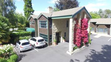A building with a stone facade, green trim, and a parking lot with two white cars.