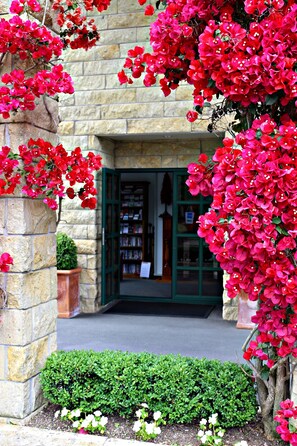 A stone building with a green door, surrounded by red flowers and a green hedge. - Cambridge Mews (Cambridge)