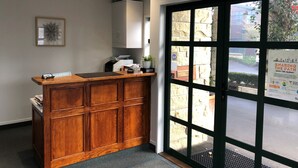 A reception desk with a wooden finish, a white wall-mounted cabinet, and a framed artwork. - Cambridge Mews (Cambridge)