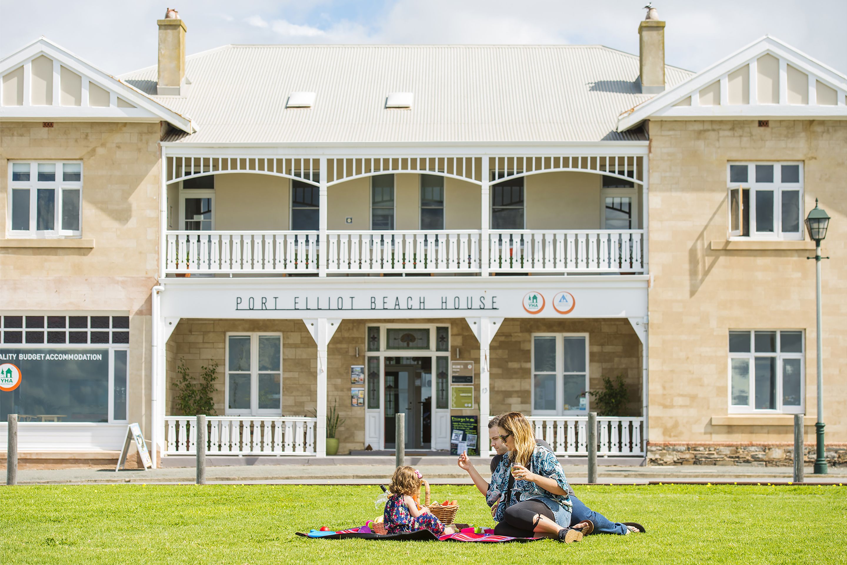 A two-story building with a balcony and a sign that reads "Port Elliot Beach House".