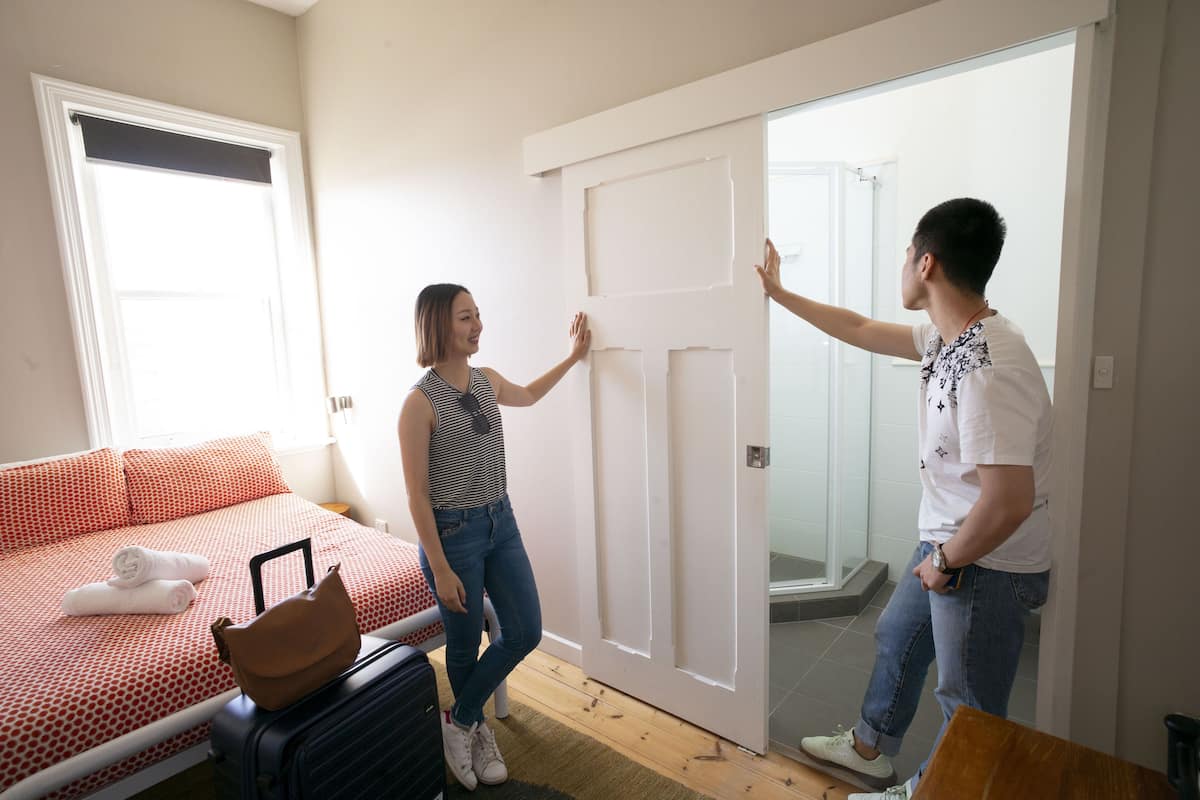 A bedroom with a bed, a suitcase, and a handbag on the floor.