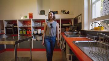 Cozinha com eletrodomésticos de aço inoxidável, uma pia e diversos utensílios de cozinha em prateleiras.
