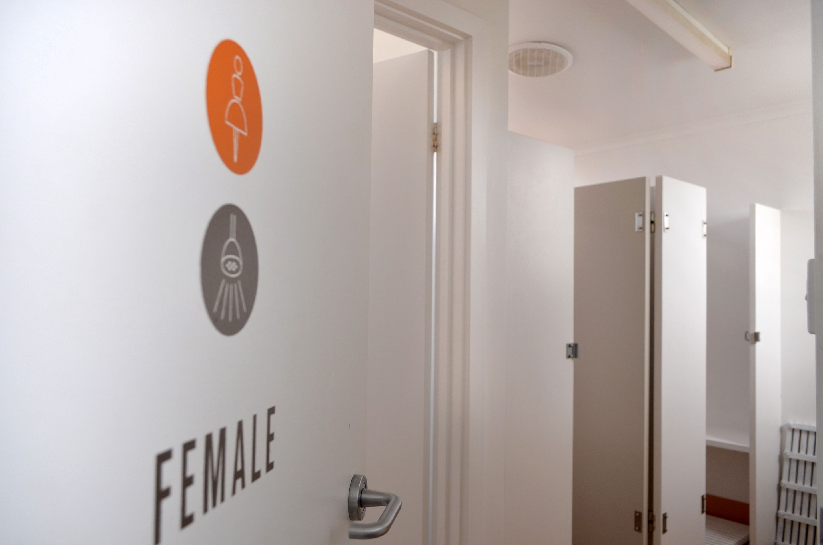A hallway with a door labeled "FEMALE" and a wall with restroom symbols.