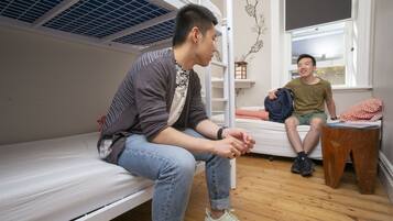 Un dormitorio con literas, suelo de madera y ventana con vistas.