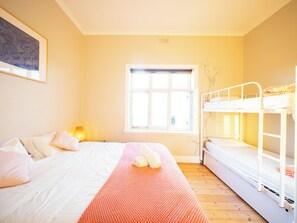 A room with a bed, a window, a bunk bed, and a wall-mounted lamp. - YHA Port Elliot (Port Elliot)