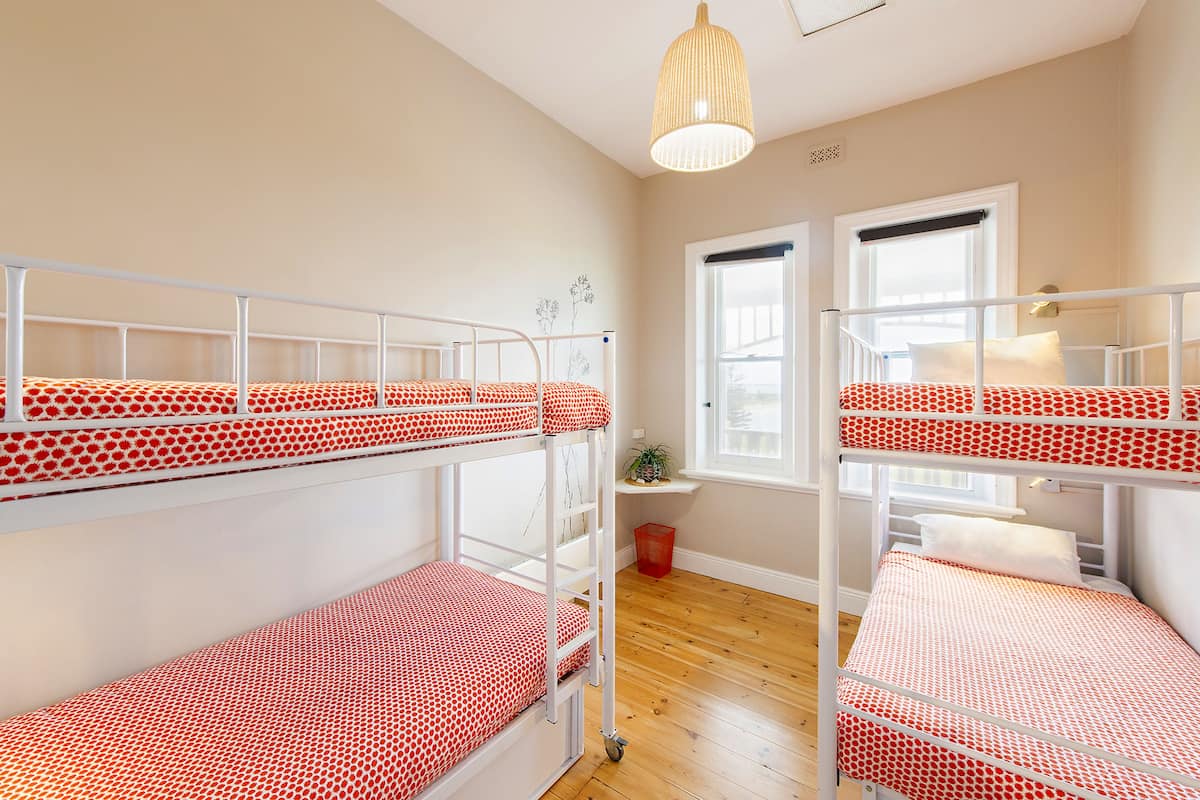 A room with bunk beds, a window, a plant, and a hanging light fixture.