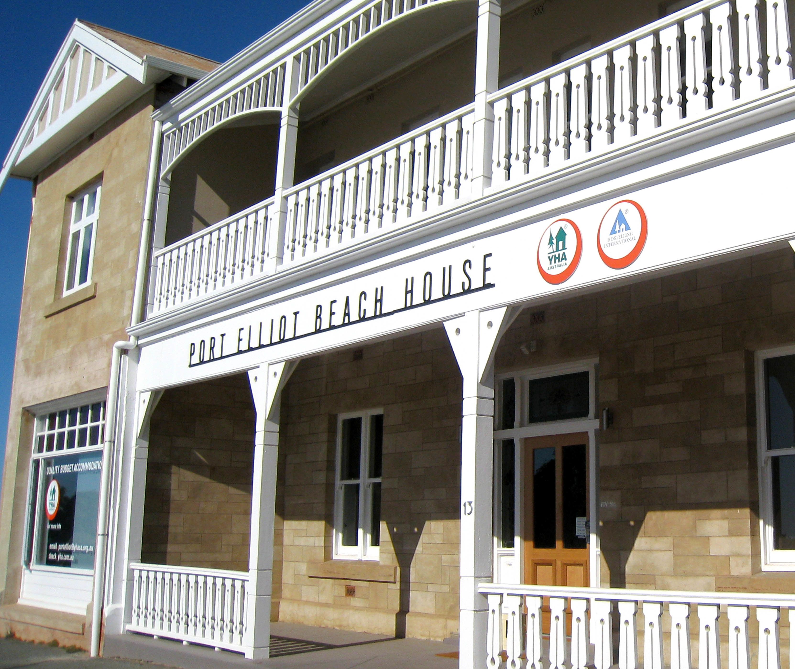 Un edificio de dos pisos con un balcón y un letrero que dice 'Port Elliot Beach House'.