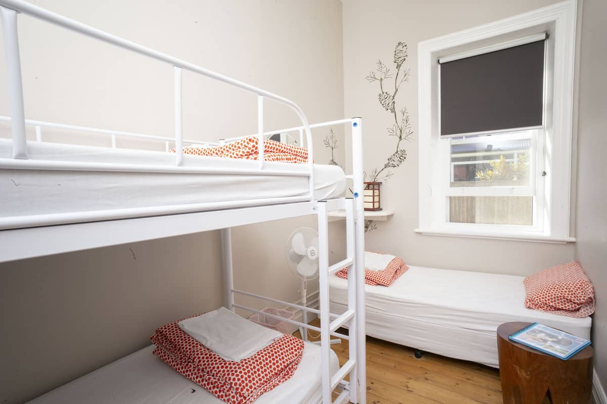 A bunk bed room with a window and a fan.
