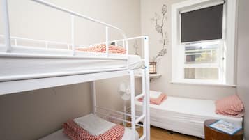 Dormitorio con literas, ventana y ventilador.