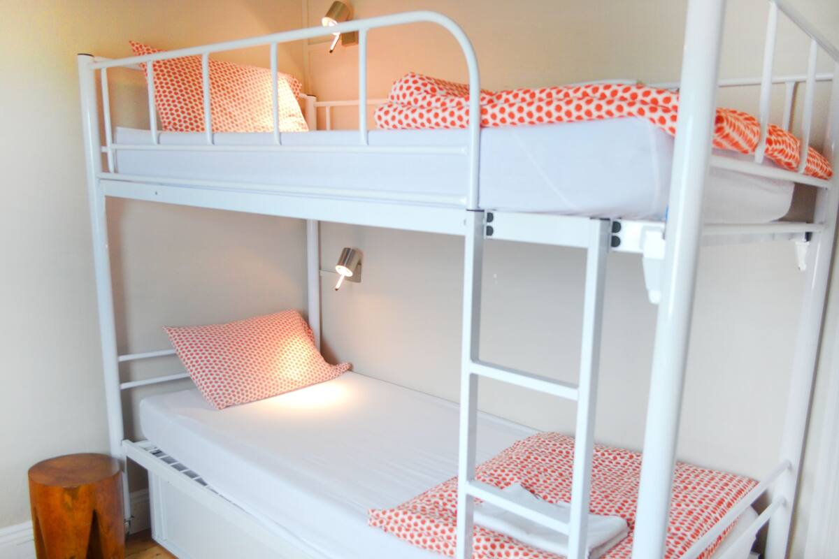 A bunk bed with two levels, each with a mattress and pillows.