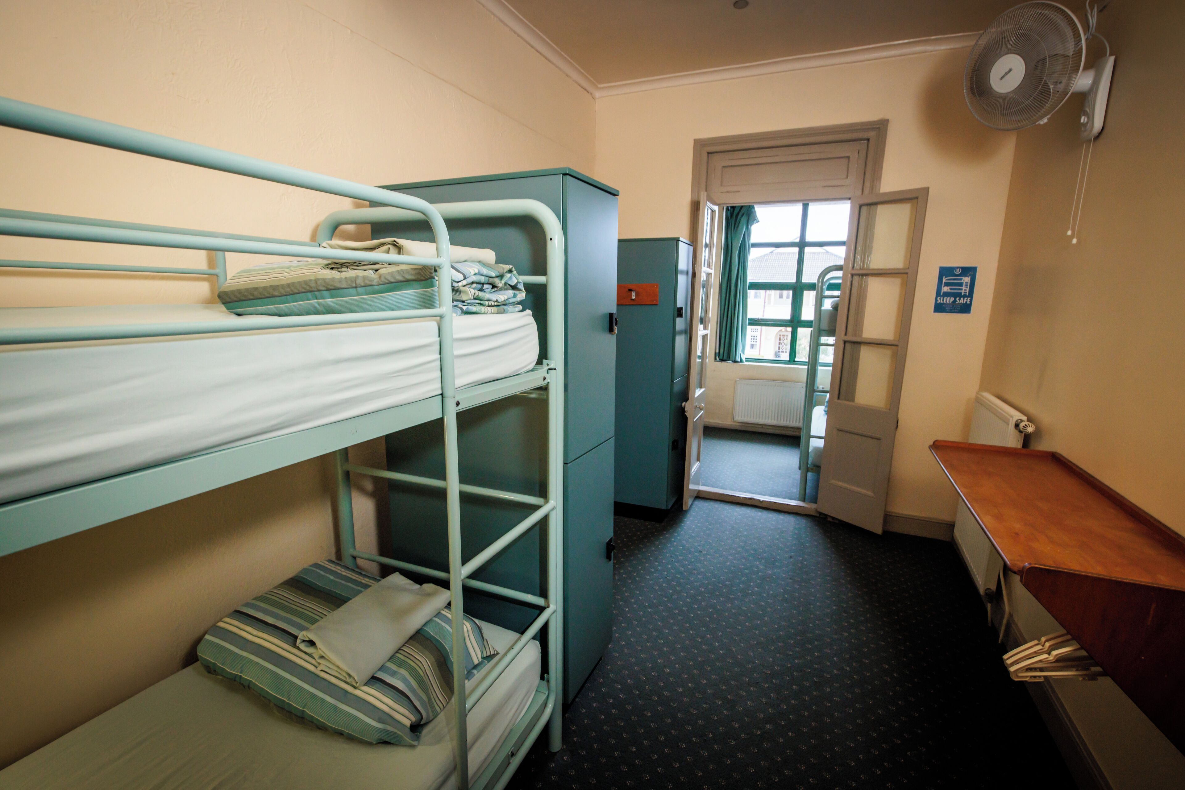 A bunk bed room with a desk and a radiator.