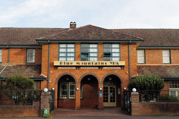 A brick building with a sign reading 'Blue Mountains YHA Backpacker Accommodation' at the entrance.