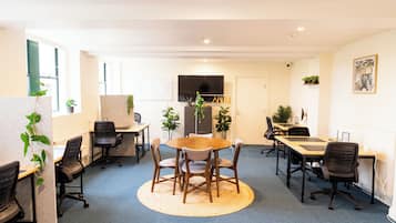 Un espace de bureau moderne avec des tables rondes, des chaises et des plantes en pot.
