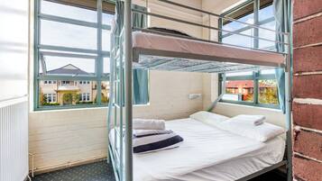 Dormitorio con literas y vista a casas desde la ventana.
