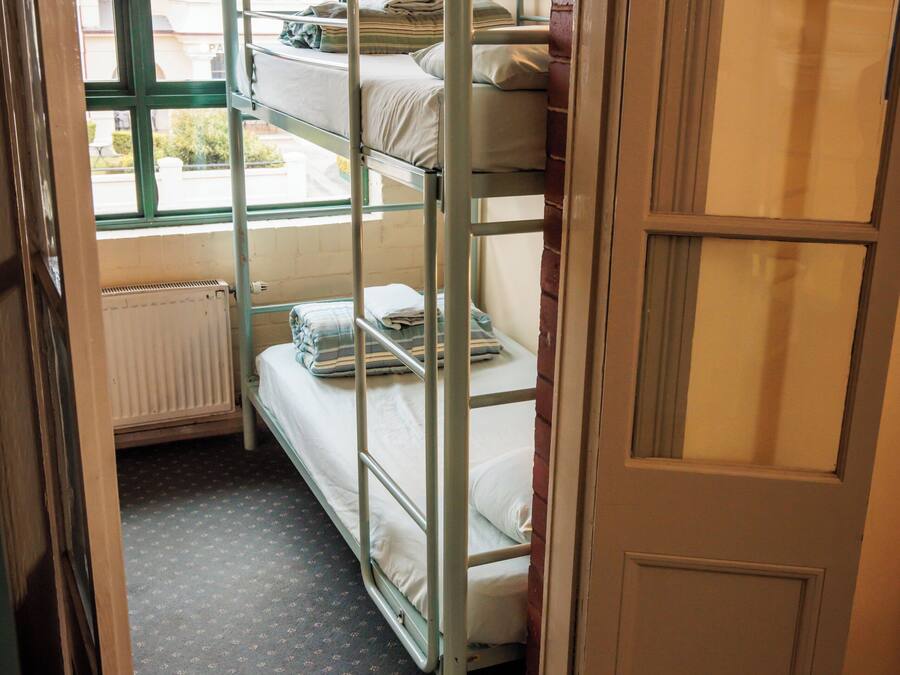 Quarto com beliche, janela, radiador e porta.