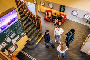 Welcome to our lobby, featuring a reception desk, comfortable seating areas, and a staircase leading to the upper floor.